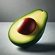 A close-up image of a sliced avocado with its pit visible, placed elegantly on a smooth, gray background. The avocado is cut open to reveal its creamy
