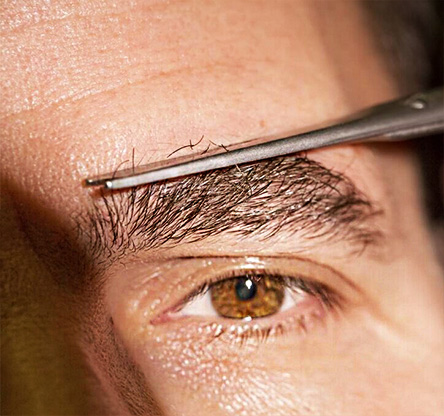 Macro illustration of a male eyebrow being delicately trimmed with scissors, showing maintenance needed after eyebrow transplant for natural appearance