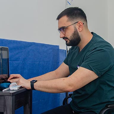 A doctor in a dark green uniform is carefully adjusting and setting up medical equipment in preparation for an upcoming surgery