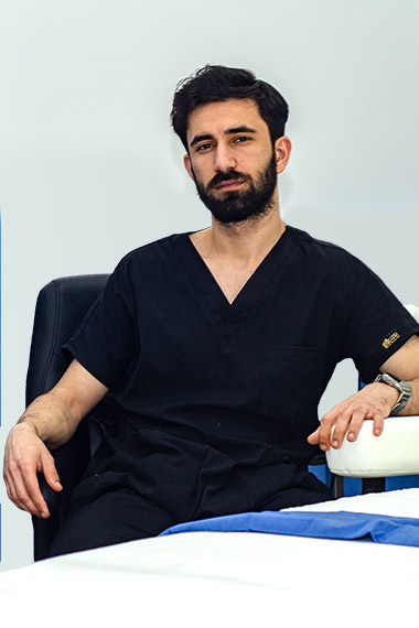 A man in black medical uniform is sitting by the operating table.