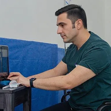 Dr. Onez Özkaya Lead Hair Transplant Specialist working at computer in clinic